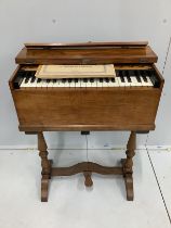 A small early 20th century walnut cased harmonium, with single bellows action, on fixed turned