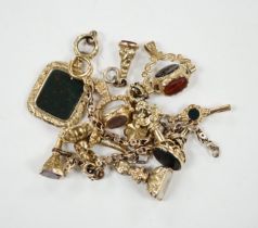 An early 20th century yellow metal charm bracelet (a.f.), hung with five assorted watch keys,