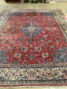A Persian brick red ground carpet, 382 x 300cm (severely worn in patches)