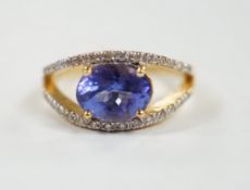 A modern 18ct gold and singe stone oval cut tanzanite ring, with diamond chip set borders, size N,