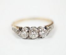 A yellow metal and three stone diamond set ring, with six stone diamond chip set shoulders, size