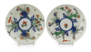 A pair of Chinese wucai saucer dishes, Kangxi period, decorated with flowering plants and insects,