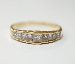 A modern 18ct gold and graduated nine stone princess cut diamond set half hoop ring, size L, gross