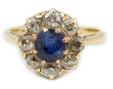 An 18ct gold, sapphire and diamond cluster ring, the central round cut sapphire bordered by old