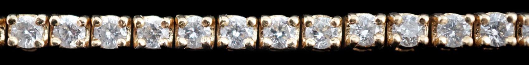 A modern 18ct gold and fifty nine stone round brilliant cut diamond set line bracelet, the stones