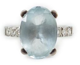 A modern 18ct white gold and single stone oval cut aquamarine set ring, with six stone diamond set