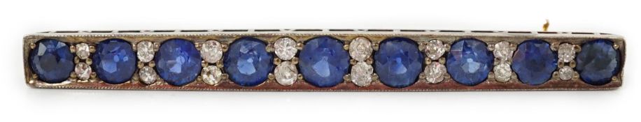 An Edwardian gold and graduated nine stone round cut sapphire set bar brooch, with round cut diamond