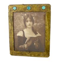 An Arts & Crafts brass picture frame, of rounded rectangular form, the top inset with three