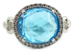 A modern 18ct white gold and facetted oval cut blue topaz set dress ring, with diamond chip set