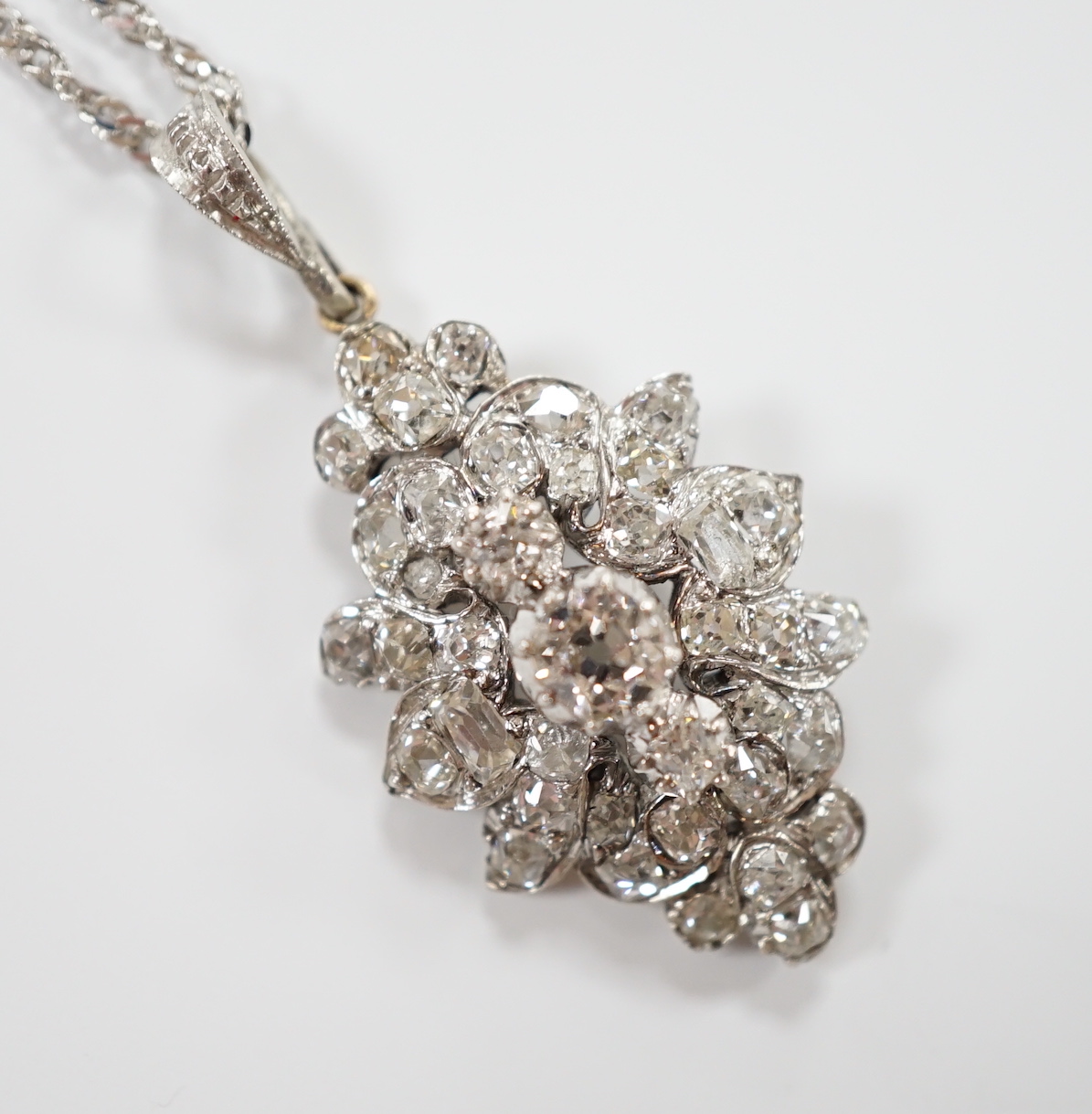 A white metal and diamond cluster set oval pendant, 27mm, on 9kt white metal chain, gross weight 5.8