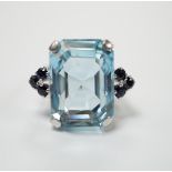 An 18ct white metal and single stone emerald cut aquamarine set dress ring, with six stone
