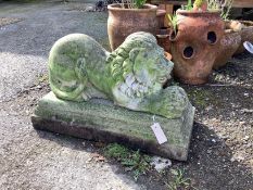 A reconstituted stone recumbent lion garden ornament on base, width 66cm, depth 28cm, height 42cm