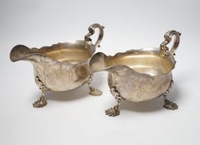 A pair of Edwardian silver sauce boats with shell knees, on three fluted feet, Carrington & Co,