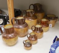 Eight Doulton stoneware jugs and a tyg, largest 27cm high