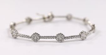 A modern 18k white metal and diamond cluster set flower head line bracelet, 17.5cm, gross weight 8.4