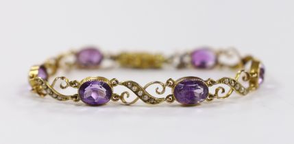 An early 20th century 9ct, amethyst and seed pearl cluster set bracelet, with carved barrel shaped