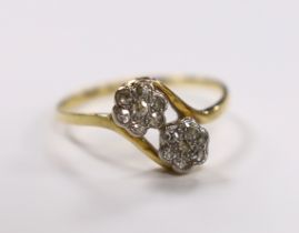 A yellow metal and diamond cluster set double flower head crossover ring, size N/O, gross weight 2