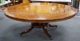 A reproduction George III style circular mahogany extending dining table with detachable segmental
