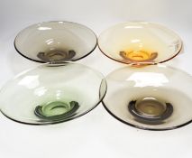 Four colour tinted glass dishes, largest 28cm diameter