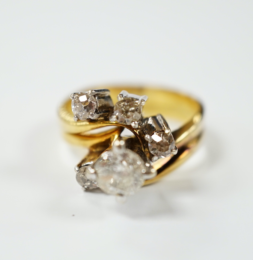 A yellow metal and graduated five stone diamond cluster set dress ring, in a raised setting, size