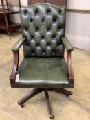 A reproduction mahogany and buttoned green leather swivel desk chair, width 60cm, depth 58cm, height