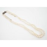 A double strand graduated cultured pearl necklace, with paste set white metal clasp, 44cm.