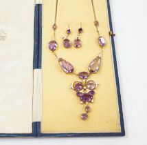 An early 20th century yellow metal, amethyst and enamel set suite of jewellery, comprising a drop