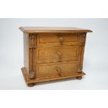 A miniature oak chest of drawers and contents (miniature bisque headed dolls and linen) height 22cm