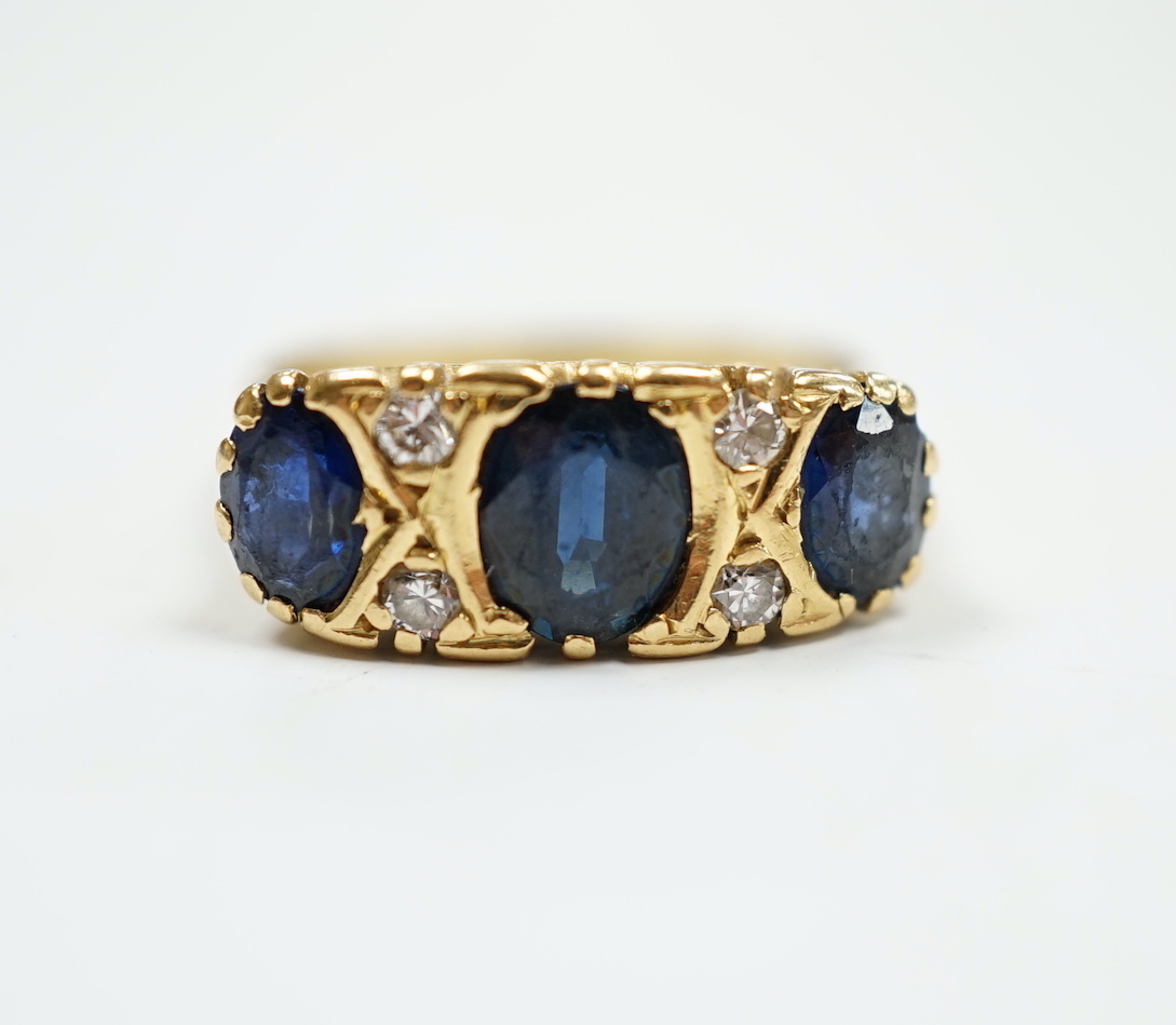 An 18ct and three stone sapphire set half hoop ring, with diamond chip spacers, size O, gross weight