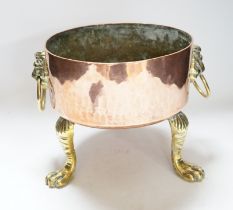 A heavy copper planter or cooking pot, with cast brass lion mask and ring handles, on brass claw