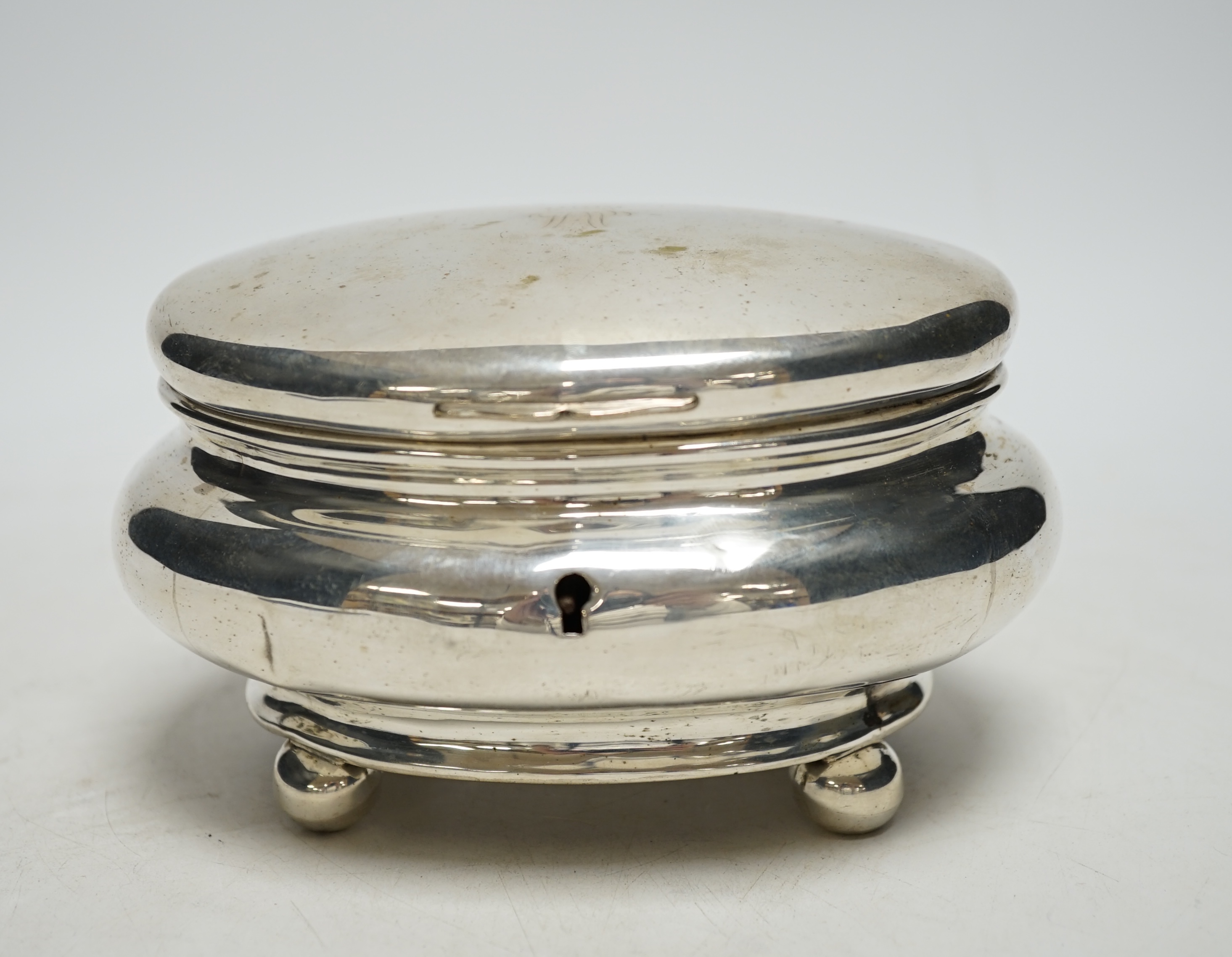 A 19th century German? white metal oval tea caddy, on bun feet, lacking key, width 16cm, 8.8oz.