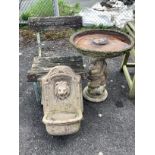 A composition faux marble lion mask wall fountain, a slatted wrought iron garden chair and a