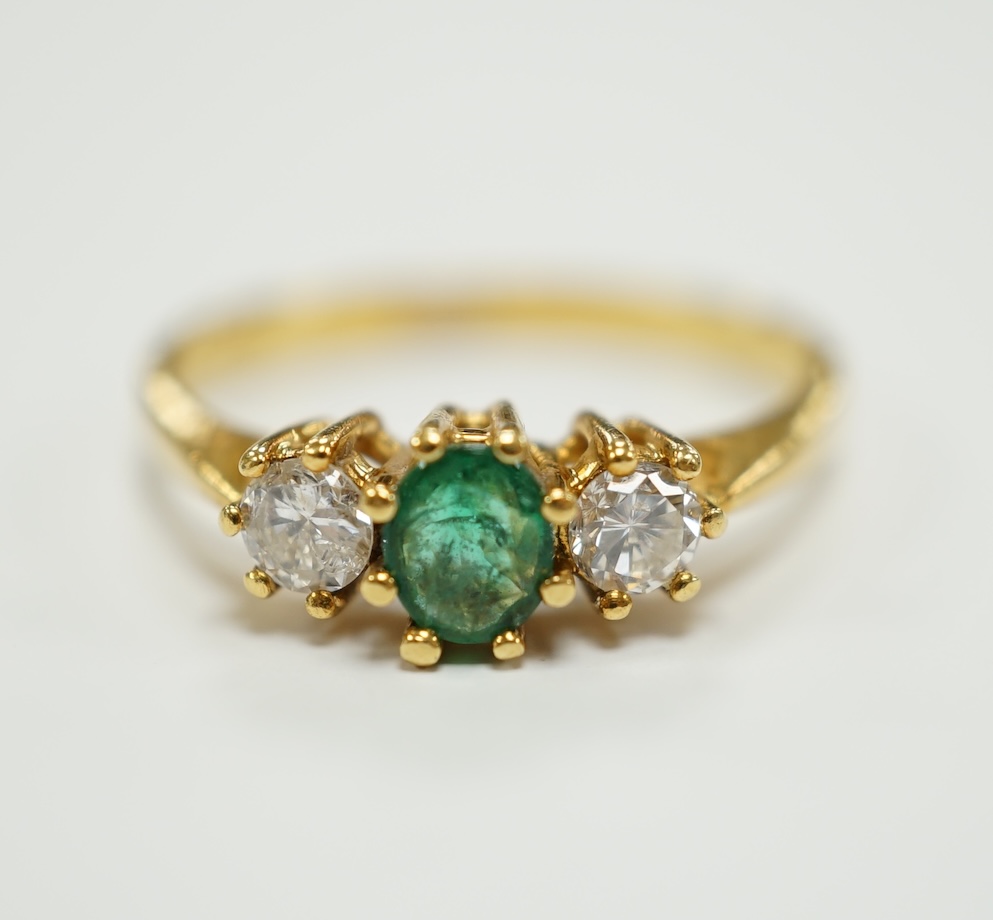 A modern 18ct gold, emerald and diamond set three stone ring, size P, gross weight 3.2 grams.