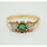 A modern 18ct gold, emerald and diamond set three stone ring, size P, gross weight 3.2 grams.