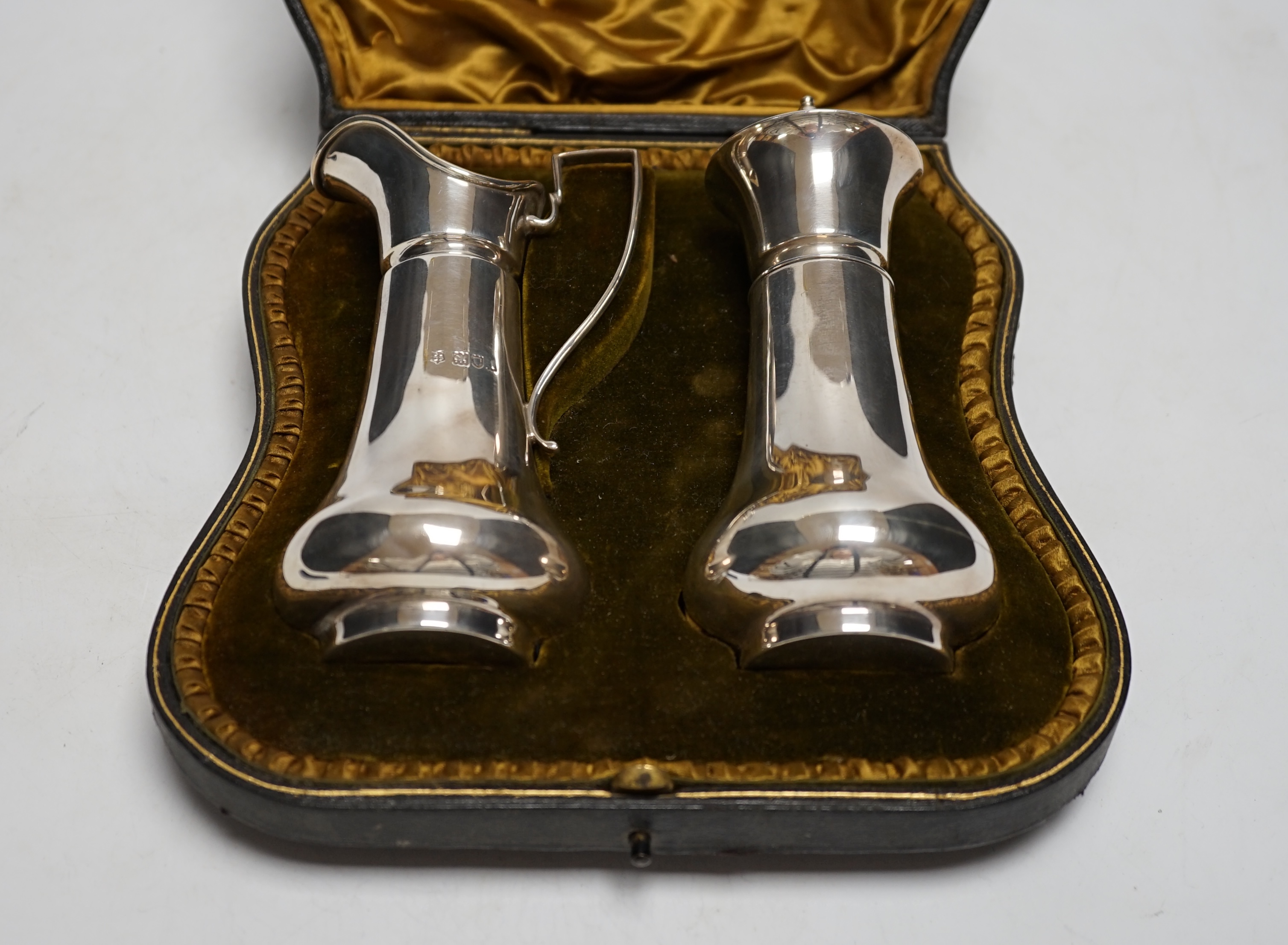 An Edwardian cased silver strawberry and cream set, comprising a cream jug and sugar sifter, by