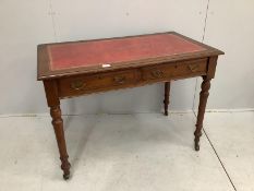 A late Victorian oak two drawer writing table, with red leather inset top, width 106cm, depth