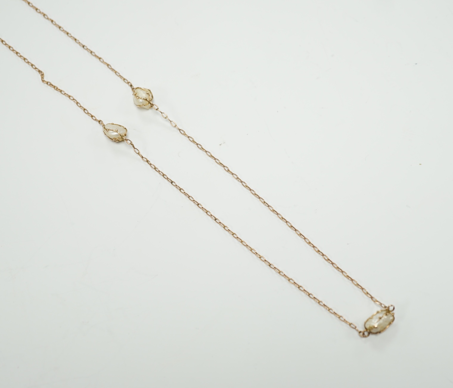 An early 20th century 9ct and eleven stone baroque pearl set long chain, 160cm, gross 13.2 grams.