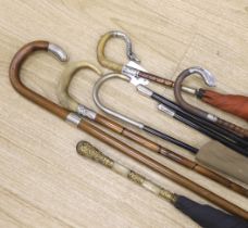 Various vintage umbrellas and walking sticks, three with silver mounted handles and two ebonised