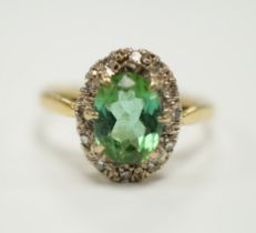 A modern 18ct gold, green tourmaline and diamond set oval cluster ring, size O/P, gross weight 3.5