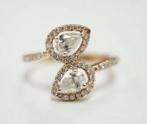 A modern 18k and two stone pear cut diamond set cross-over ring, with diamond chip border and