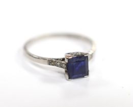 A white metal (stamped plat) and single stone square cut sapphire set ring, with diamond chip set