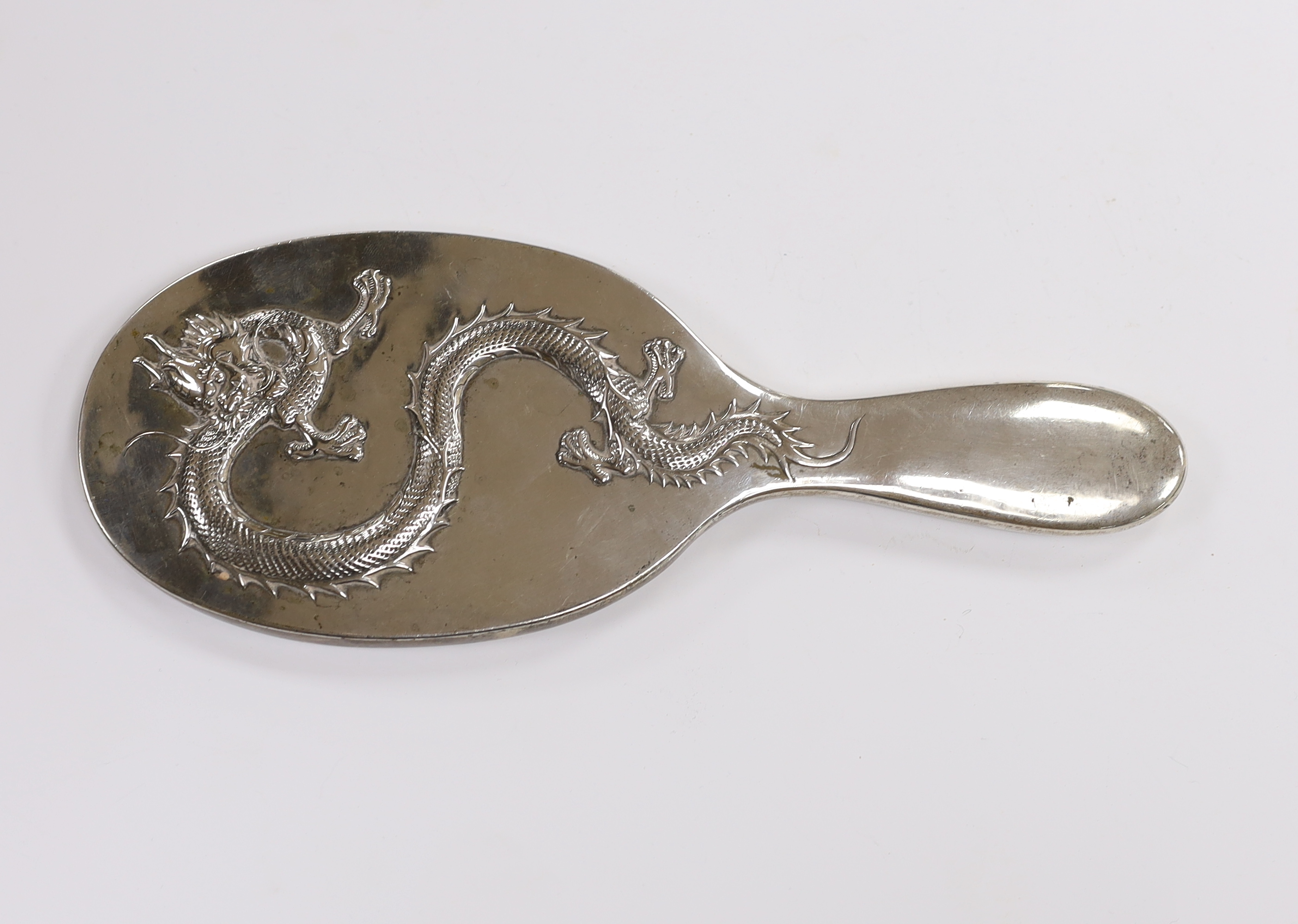 A Chinese Export white metal mounted oval hand mirror, decorated with a dragon, 25.2cm.