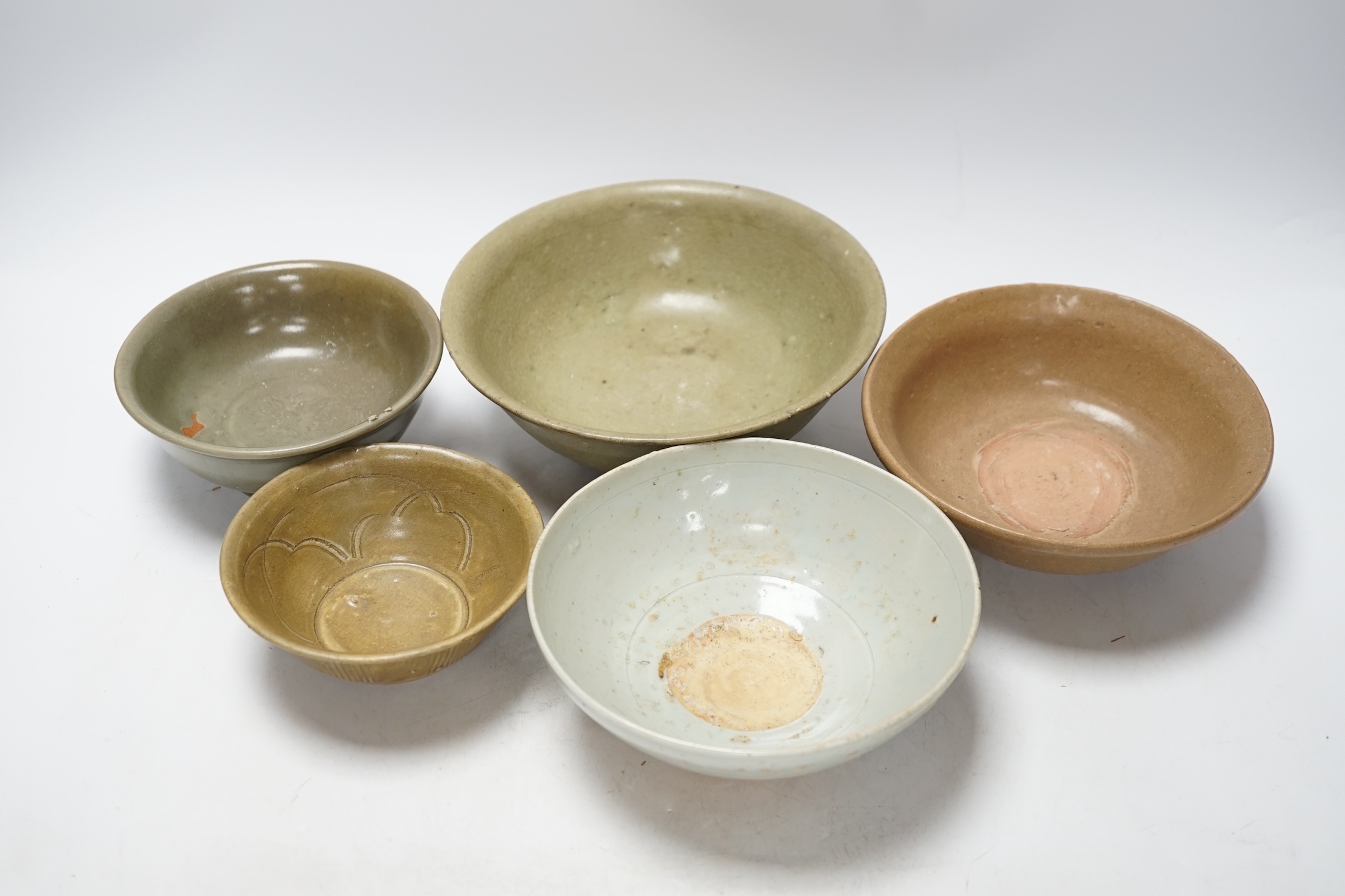 A group of four Chinese Longquan or Yue ware celadon bowls and a Qingbai bowl, Song-Yuan dynasty,