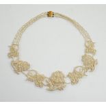 A cased Regency twin strand seed pearl choker necklace with scrolling floral motifs and yellow metal