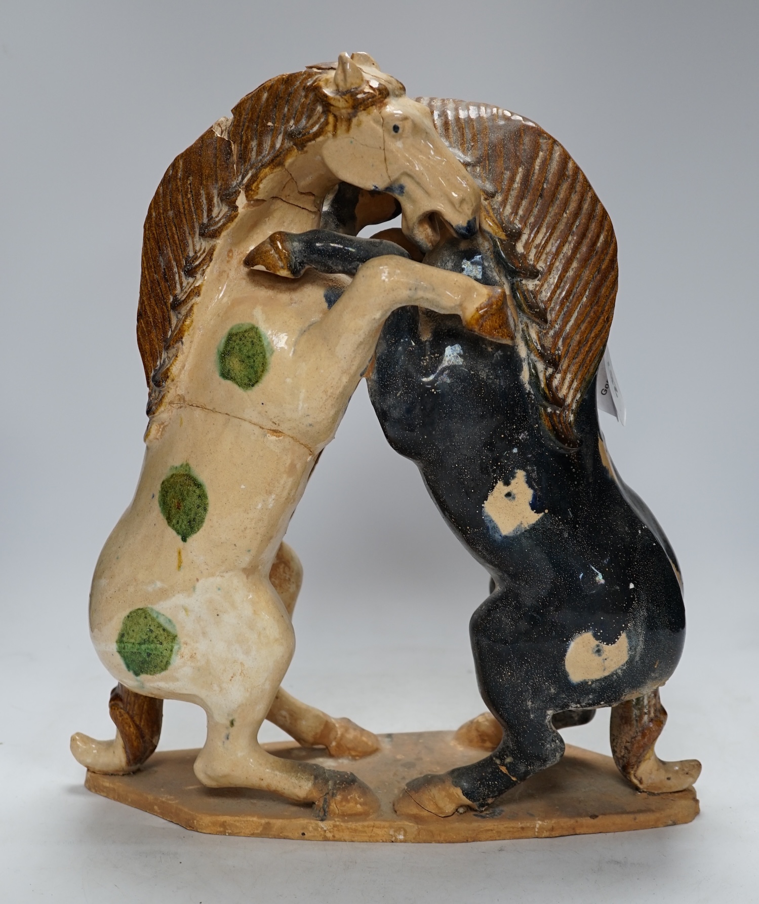 A Chinese sancai glazed group of fighting horses, Tang or later, 39cm high