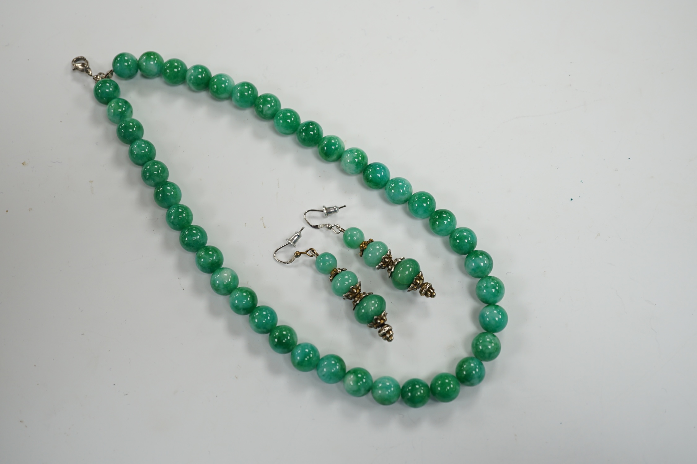 A single strand jadeite bead necklace, 41cm and a pair of jadeite earrings, stamped 18k. - Image 2 of 3