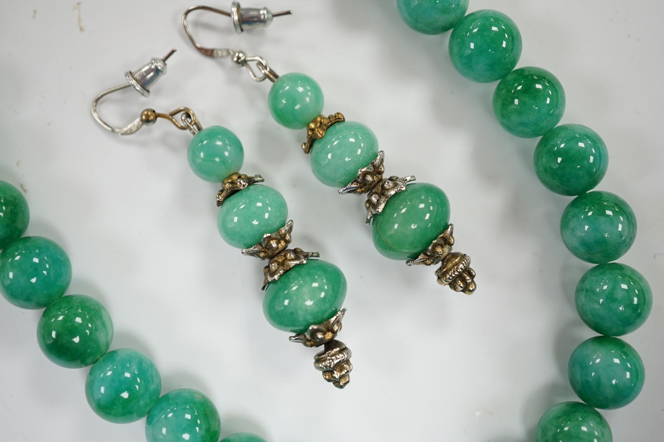 A single strand jadeite bead necklace, 41cm and a pair of jadeite earrings, stamped 18k. - Image 3 of 3