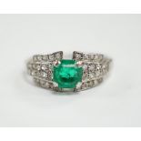 A white metal and octagonal cut emerald set dress ring, with diamond cluster set shoulders, size