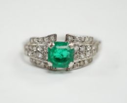 A white metal and octagonal cut emerald set dress ring, with diamond cluster set shoulders, size