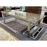 A rustic rectangular driftwood dining table, on a stainless steel base with plate glass top,